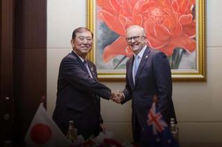 Two leaders shake hands as they pose for a photograph.