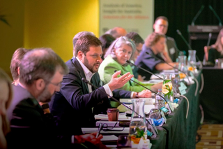 Person talking and gesturing at roundtable discussion